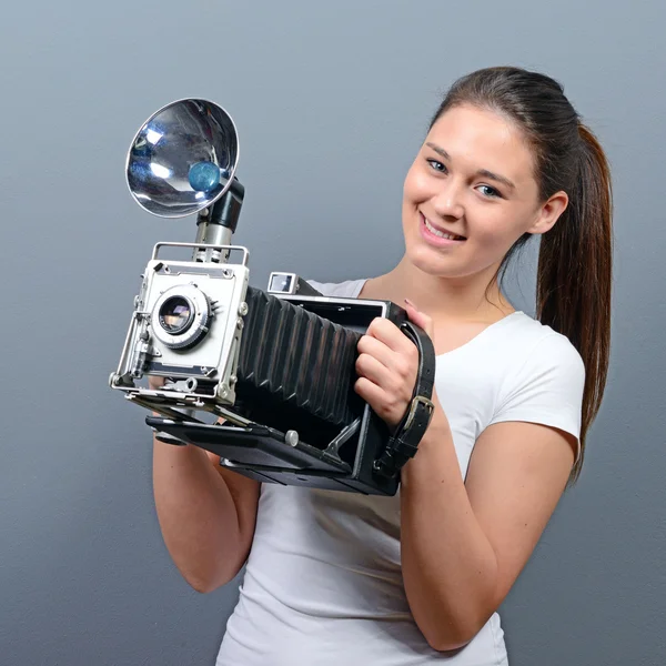 Retrato de una mujer joven sosteniendo cámara retro contra la espalda gris — Foto de Stock