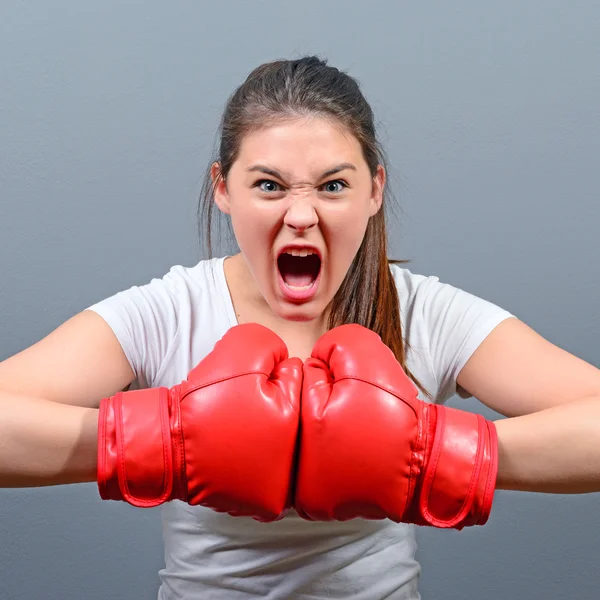 Retrato de mujer enojada posando con guantes de boxeo contra gris b — Foto de Stock