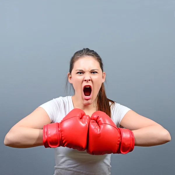 Retrato de mujer enojada posando con guantes de boxeo contra gris b — Foto de Stock