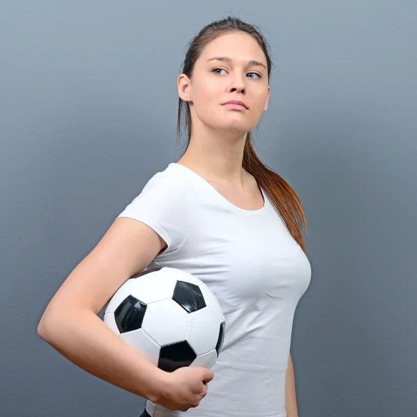 Retrato de menina segurando futebol contra fundo cinza — Fotografia de Stock