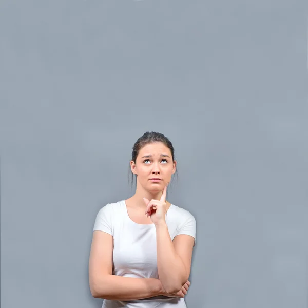 Retrato de mujer joven reflexiva mirando abpve contra ba gris —  Fotos de Stock