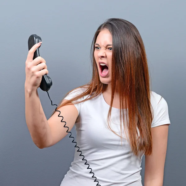 Portrait of woman having unpleasant phone calll against gray bac — Stock Photo, Image