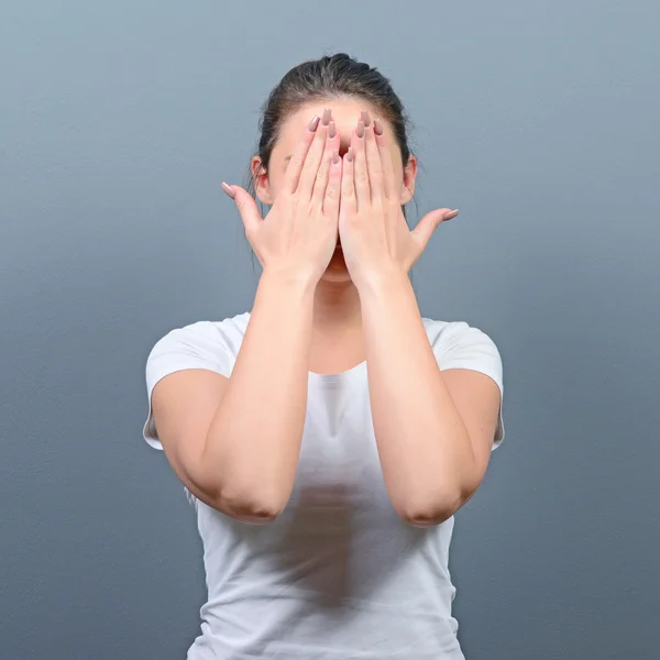 Portrait of woman hiding her face with both hands against gray b — Stock Photo, Image