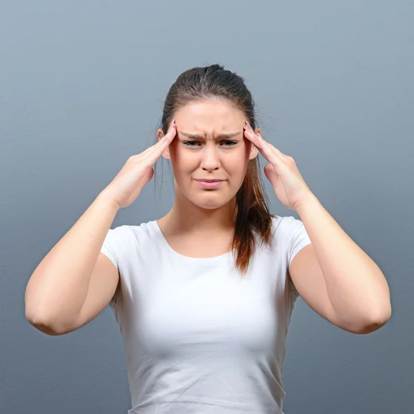 Portret van een vrouw met hoofdpijn tegen de grijze achtergrond — Stockfoto