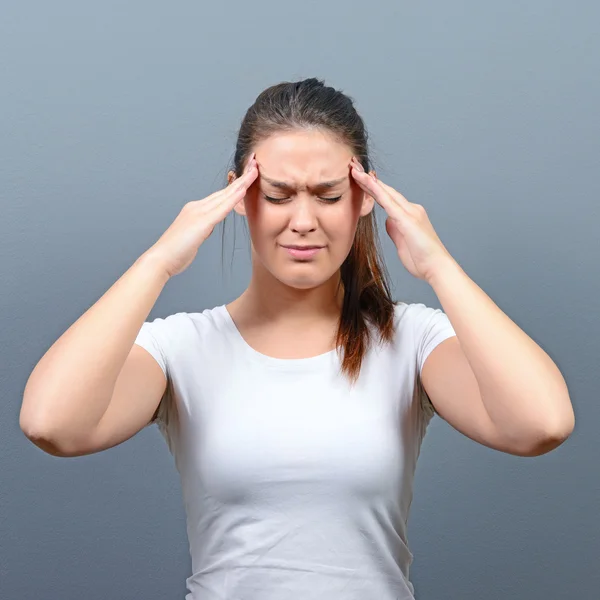 Porträt einer Frau mit Kopfschmerzen vor grauem Hintergrund — Stockfoto
