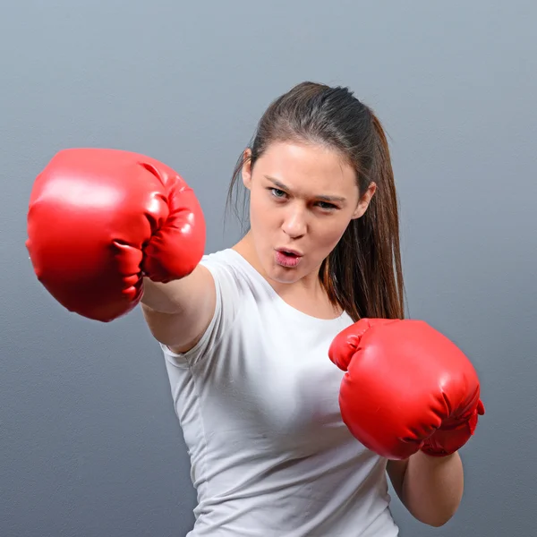 Retrato de mujer joven posando con guantes de boxeo contra gris b — Foto de Stock