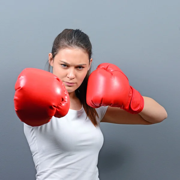 Retrato de mujer joven posando con guantes de boxeo contra gris b — Foto de Stock