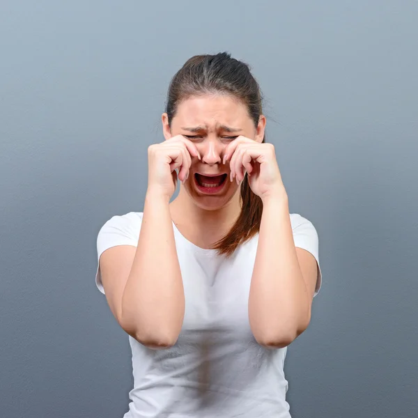 Kobieta płacze i ocierając łzy na szarym tle — Zdjęcie stockowe