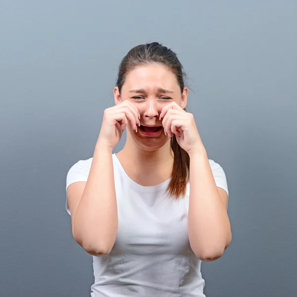 Woman crying and wiping tears against gray background — Stock Photo, Image