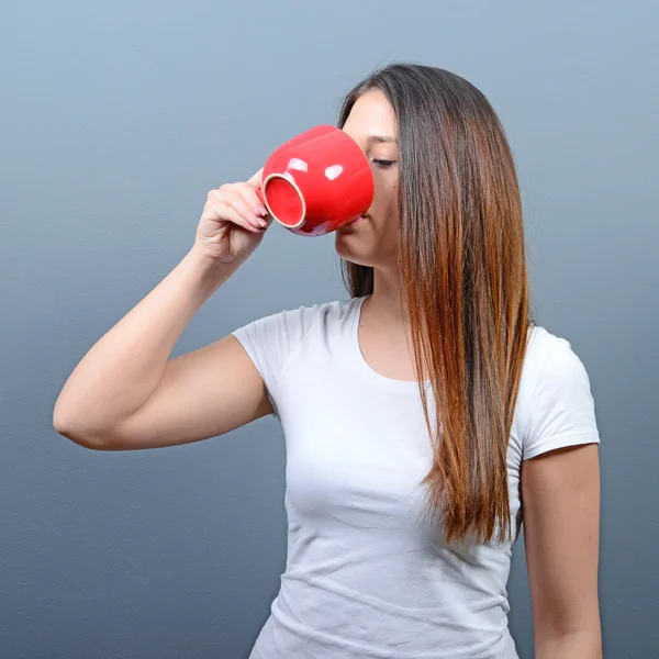 Gri arka plan karşı sıcak içecek içme kadın