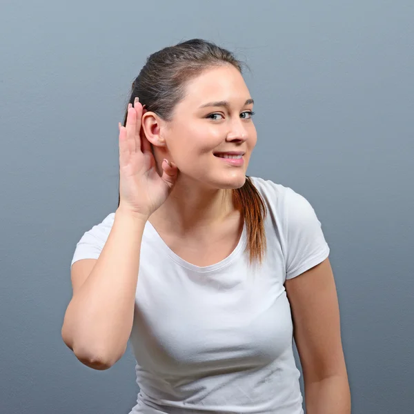 Mujer escuchando con concepto de mano a oreja sobre fondo gris —  Fotos de Stock