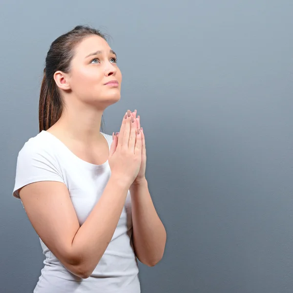 Woman praying about something or begging for mercy against gray — Stock Photo, Image