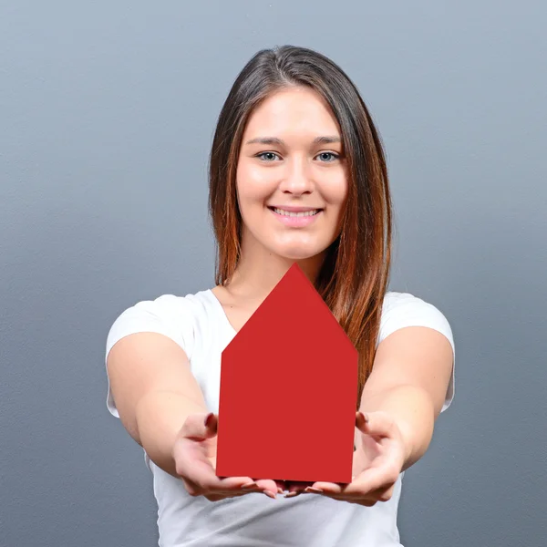 Jovem segurando casa contra fundo cinza - Imobiliário — Fotografia de Stock