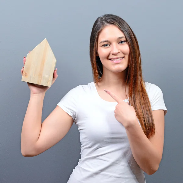 Mujer joven señalando la casa sobre fondo gris - Real es — Foto de Stock