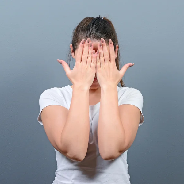 Portrait of woman hiding her face with both hands against gray b — Stock Photo, Image