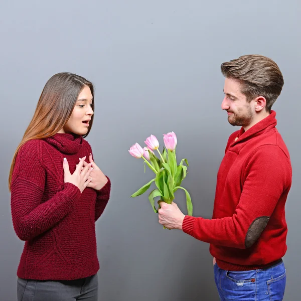 Portrait of happy young woman getting flowers from man and feeli