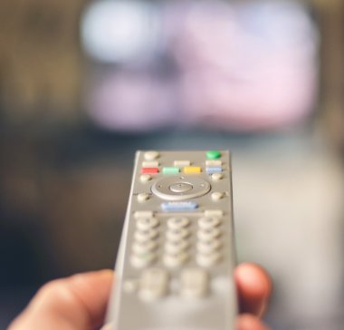 Uzaktan kumanda ile tv arka planda tutan el 