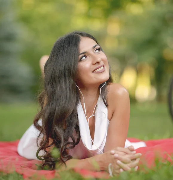 Beautiful young woman listening to music outdoors at park — Stock Photo, Image