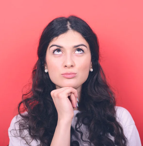 Portrait of beautiful girl thinking and looking up against red b — Stock Photo, Image