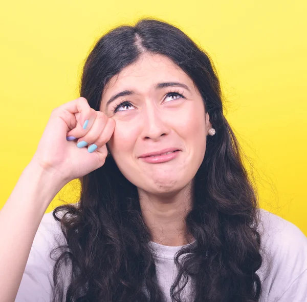 Portrait of woman crying and wiping tears against yellow backgro — Stock Photo, Image