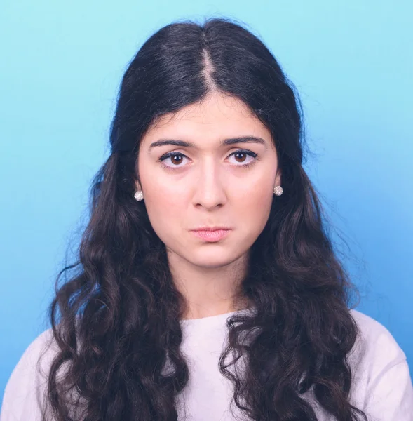 Portrait of sad girl against blue background — Stock Photo, Image