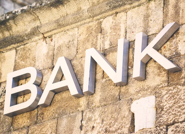 Banken tecken ristade i sten på byggnad — Stockfoto
