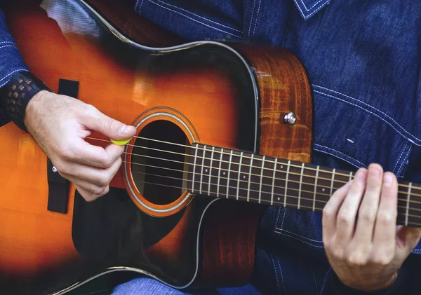 Adam akustik gitar çalıyor.