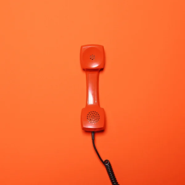 Retro-orangefarbene Telefonröhre auf orangefarbenem Hintergrund - flache Verlegung — Stockfoto