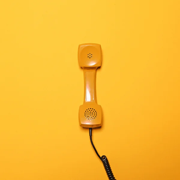 Ретро-желтая телефонная трубка на желтом фоне - Плоская кладка — стоковое фото