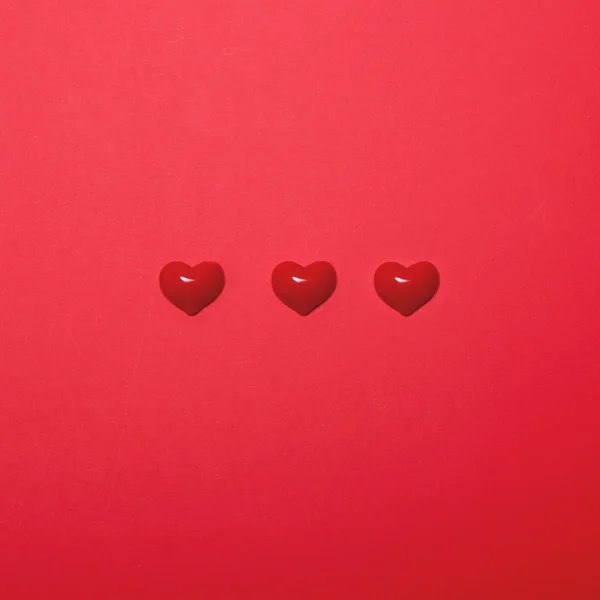 Tre små hjärtan på röd bakgrund - Minimal design — Stockfoto