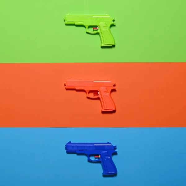 Zabawkowe pistolety na tle kolorowe - widok z góry minimalistyczny wygląd — Zdjęcie stockowe