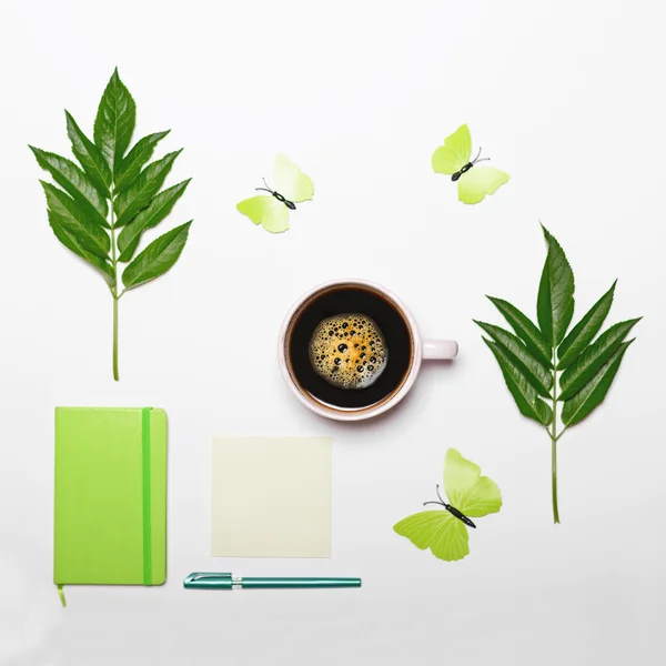 Filiżankę kawy z zielonych liści motyl książki i pióra na białym — Zdjęcie stockowe