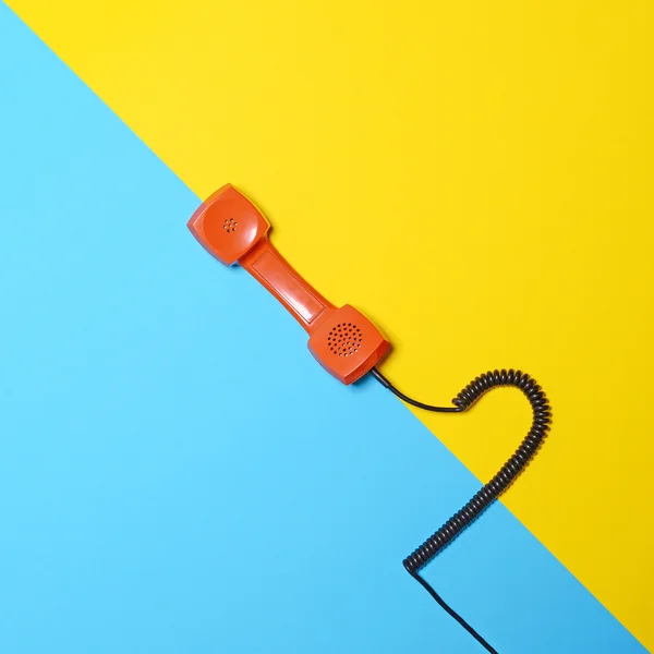 Tubo de teléfono naranja retro en fondo azul y amarillo rayado —  Fotos de Stock