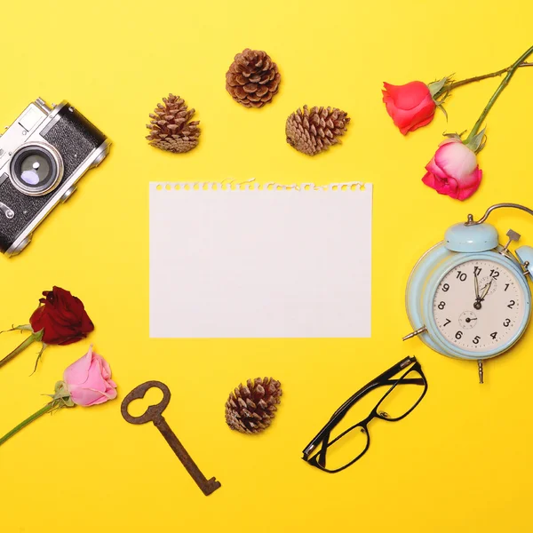 Papel en blanco con varios objetos a su alrededor sobre fondo amarillo — Foto de Stock