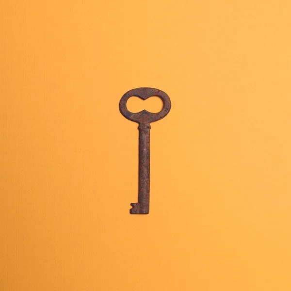 Old rusted key on yellow ocher background - Top view — Stock Photo, Image