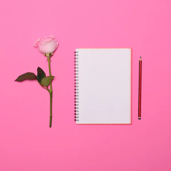 Τέλεια τριαντάφυλλο και κενό σημειωματάριο και στυλό σε ροζ φόντο - Fla — Φωτογραφία Αρχείου