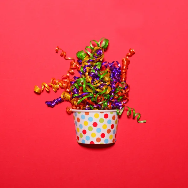 Veelkleurige confetti explosie van cup op rode achtergrond - Min — Stockfoto