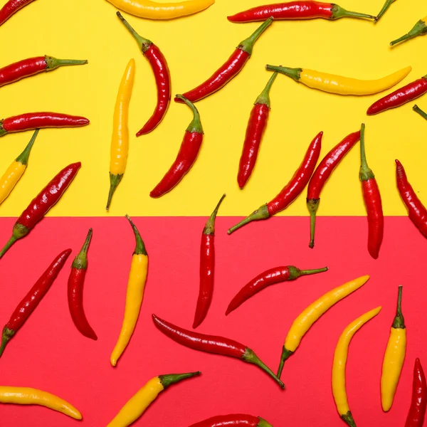 Czerwone i żółte gorące papryczkę chili na czerwonym i żółtym tle - — Zdjęcie stockowe