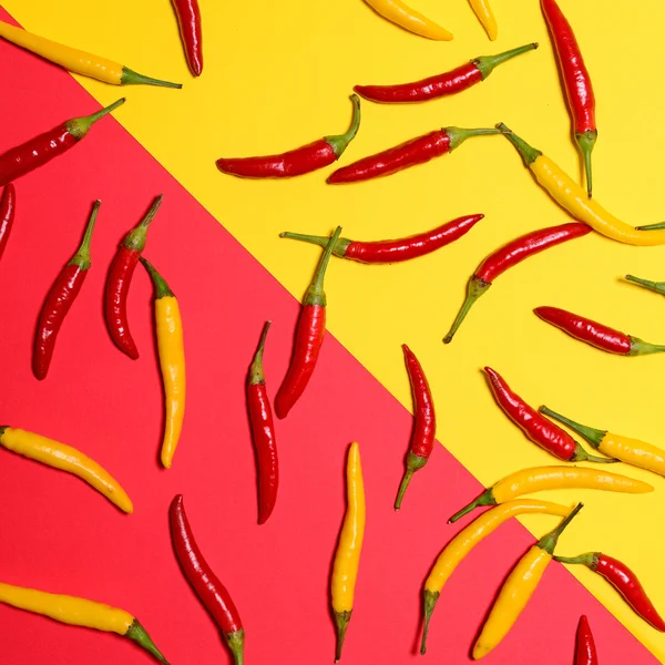 Red and yellow hot chili peppers on red and yellow background - — Stock Photo, Image