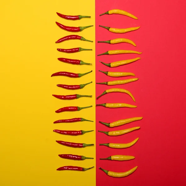 Pimientos picantes rojos sobre fondo rojo y amarillo - Puesta plana — Foto de Stock
