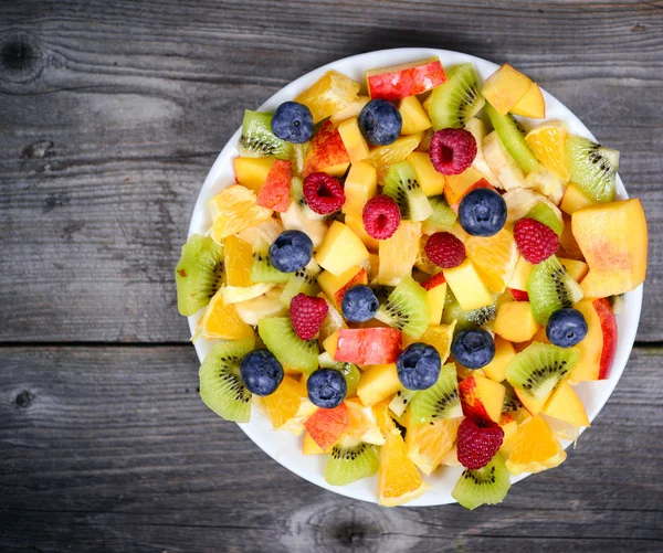 Vista superior de una ensalada de frutas frescas con plátanos kiwi naranja azul —  Fotos de Stock