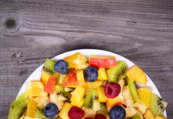 Vista superior de una ensalada de frutas frescas con plátanos kiwi naranja azul — Foto de Stock