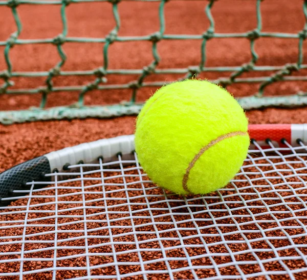 Raqueta de tenis con bola en ella arcilla en pista de arcilla — Foto de Stock