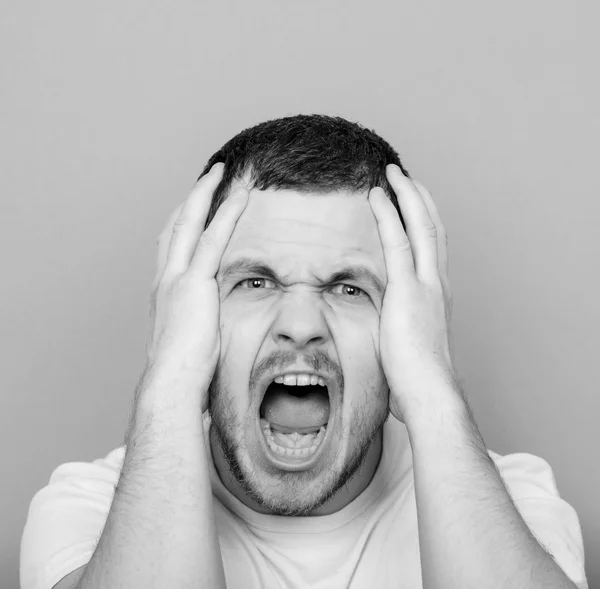 Портрет разгневанного человека, кричащего и дергающего за волосы - монохромный или — стоковое фото