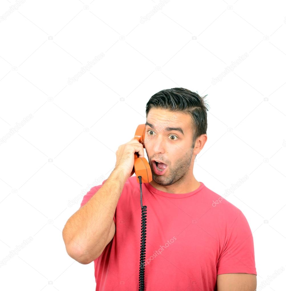 Portrait of young man in shock while talking on phone having unp