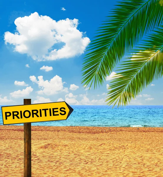 Tropical beach and direction board saying PRIORITIES — Stock Photo, Image