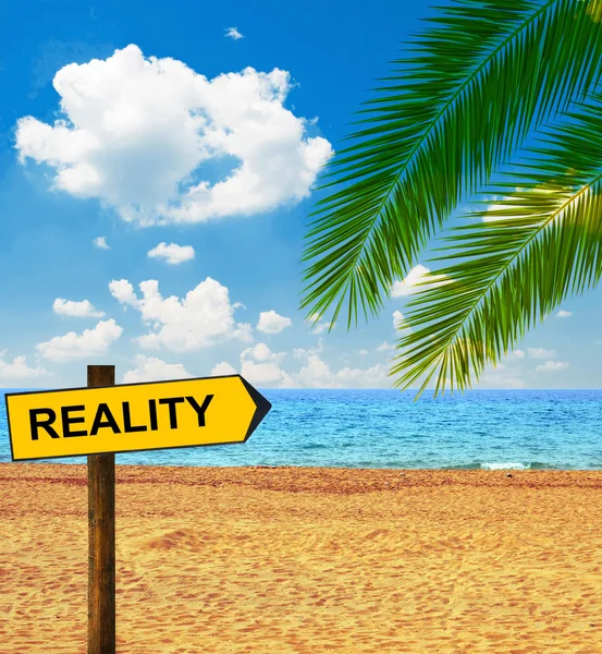 Tropical beach and direction board saying REALITY — Stock Photo, Image