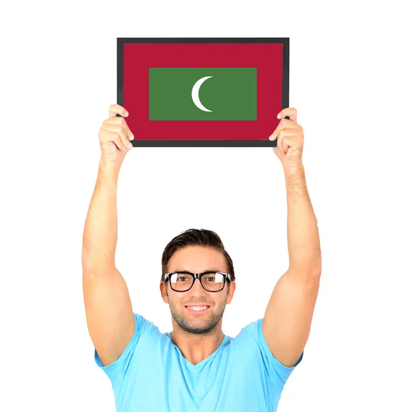 Porträtt av en ung casual man håller upp styrelse med nationella flagga Maldiverna — Stockfoto