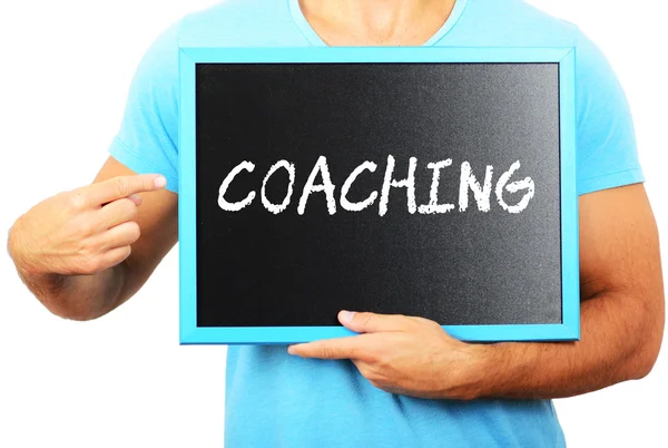 Hombre sosteniendo pizarra en las manos y señalando la palabra COACHING — Foto de Stock