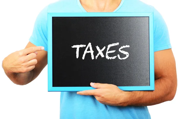 Man holding blackboard in hands and pointing the word TAXES — Stock Photo, Image